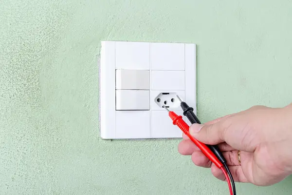 an electrician hand with a tester testing a outlet on a wall from Electrician Leander TX in Round Rock, TX - Round Rock TX